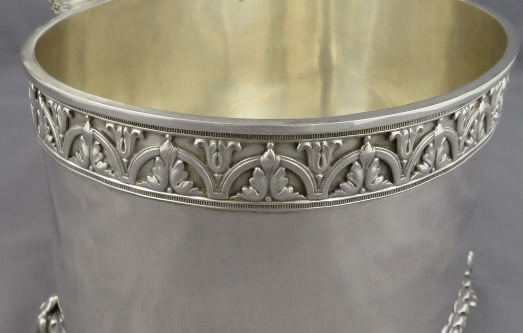 Close-up of an antique silver biscuit box or bucket with an ornate decorative band around the upper rim and a polished gold-toned interior.