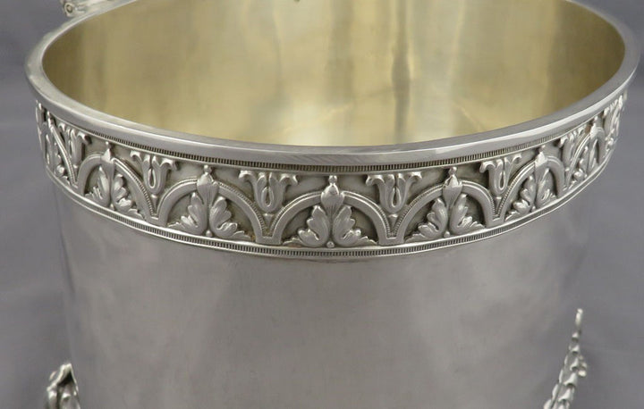 Close-up of an antique silver biscuit box or bucket with an ornate decorative band around the upper rim and a polished gold-toned interior.