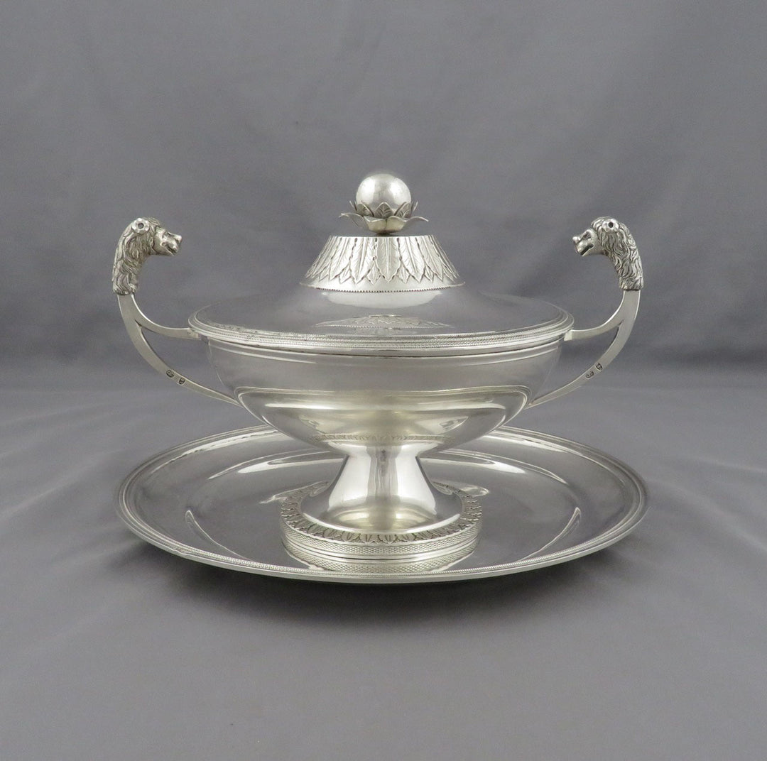An antique Italian sterling silver tureen with, Kingdom of Sardinia c. 1820,. featuring lion's head handles and a matching serving tray, set against a neutral gray background.